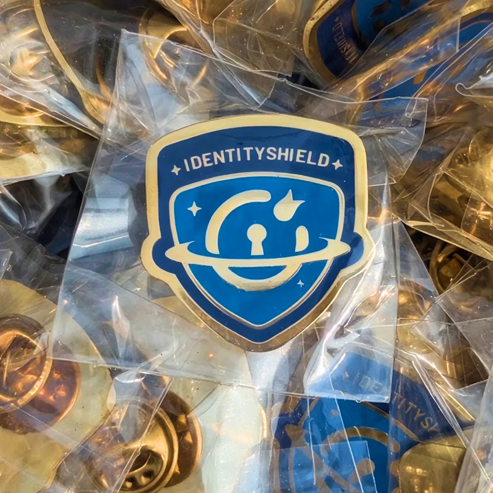 Identity Shield enamel pins in clear bags