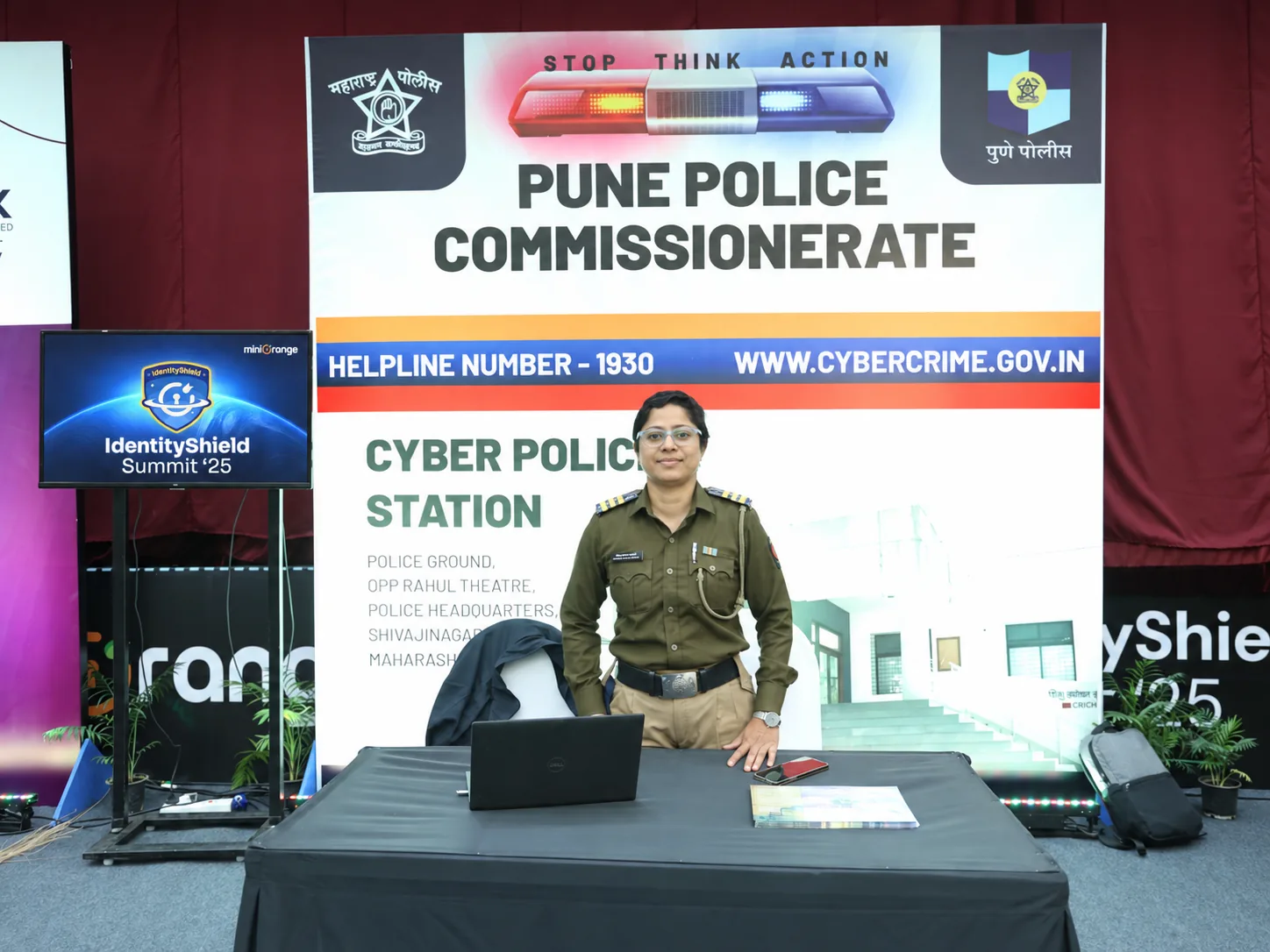 An officer standing at the Pune Police Commissionerate cyber police booth, with the helpline number 1930 on the backdrop