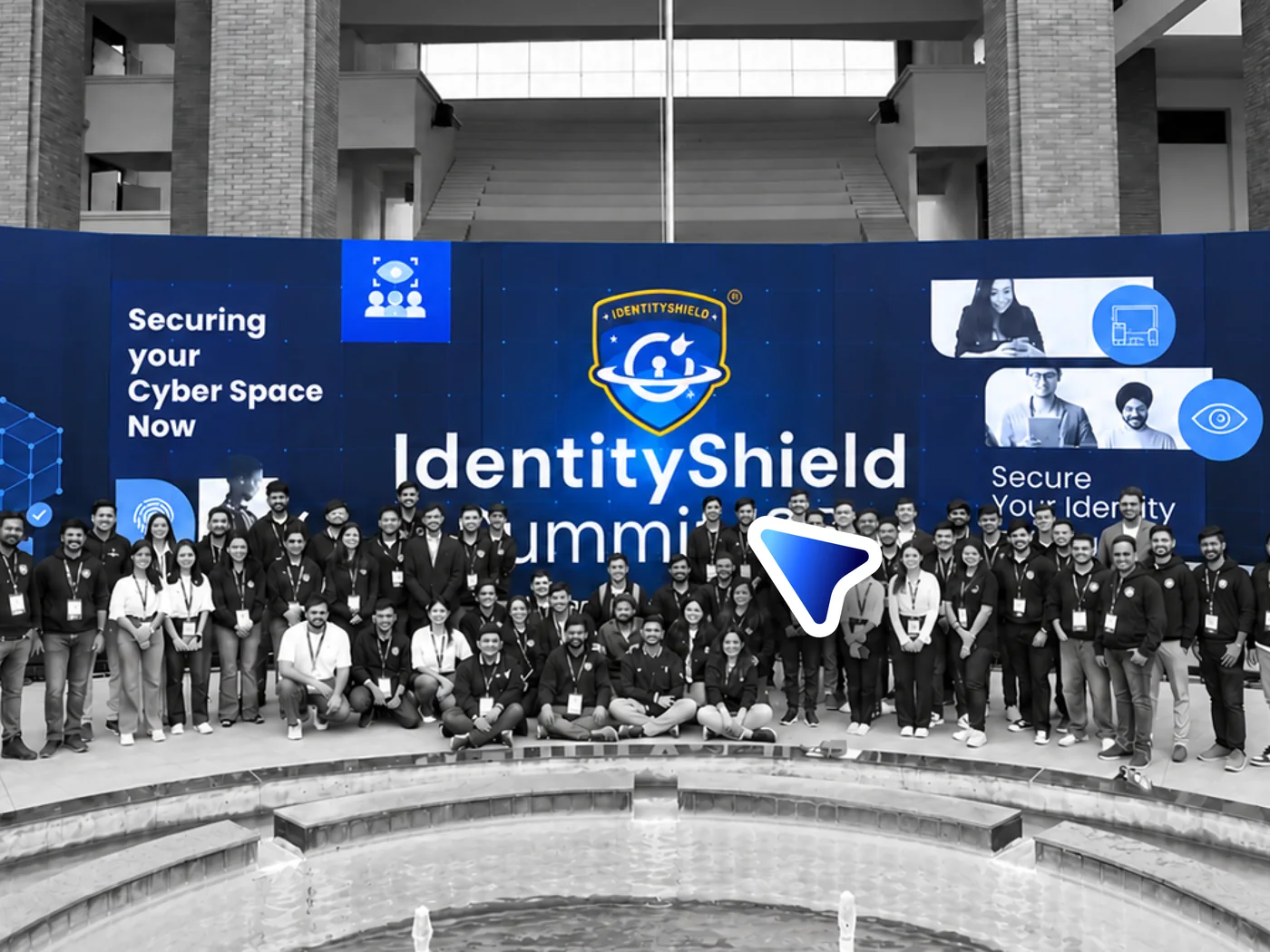 The IdentityShield Summit ’25 team in front of the blue stage backdrop, the crowd in black and white